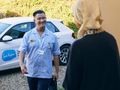 A Sue Ryder healthcare professional arrives at a person's home and smiles while greeting them at the front door